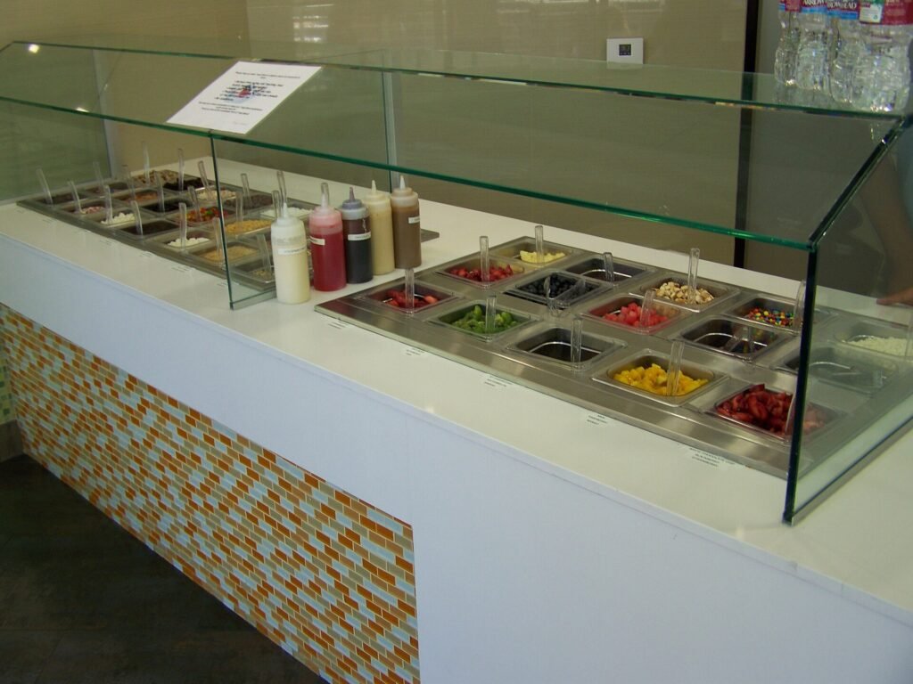 Frozen yogurt toppings bar with candy and fruit